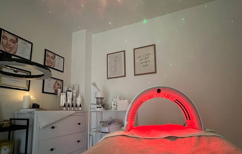 A cozy spa room with a massage table under glowing LED light therapy.