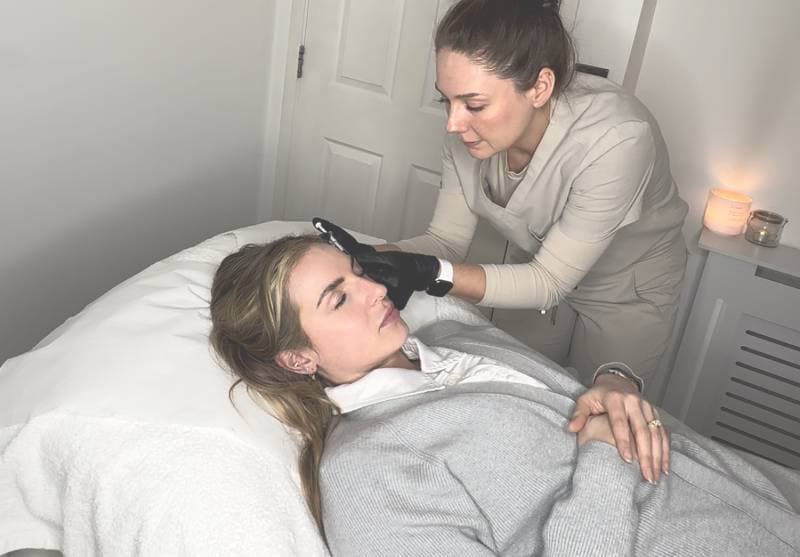 Aesthetician performing an anti-wrinkle treatment on a female client.